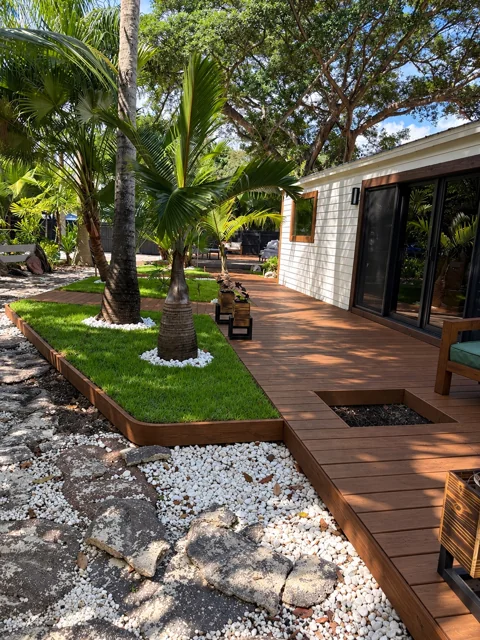 Warm wood deck beside a home with integrated palm garden beds