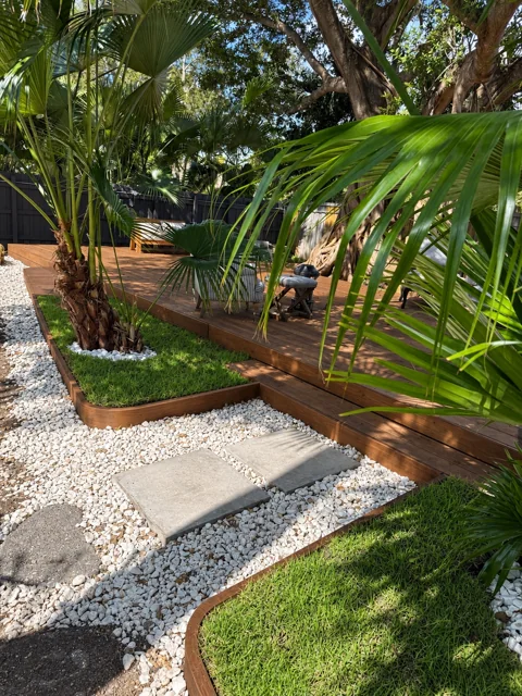 Garden pathway meeting a handcrafted wood deck and curved border
