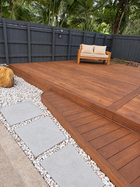 Rounded deck step beside a white stone and paver pathway