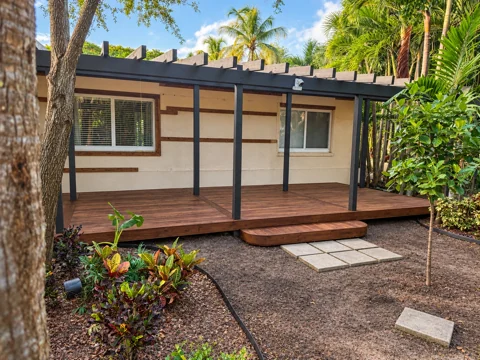 Full view of a custom wood deck with rounded entry step beneath a pergola