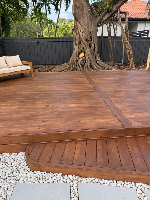 Custom wood deck with a rounded entry step beneath a mature tree